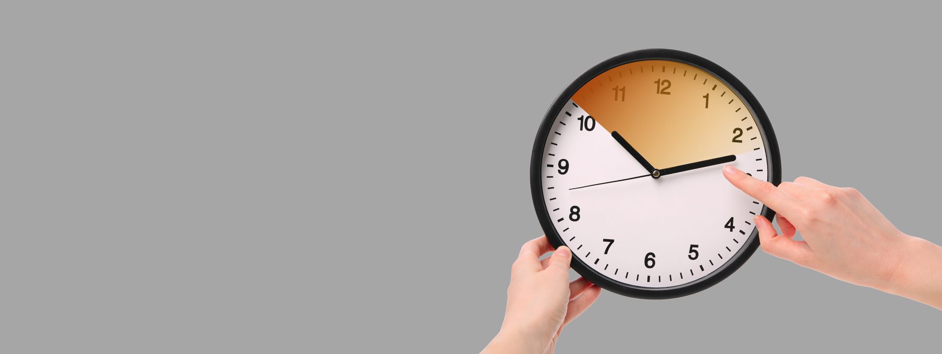 Hands adjusting the time on a wall clock for the start of daylight saving
